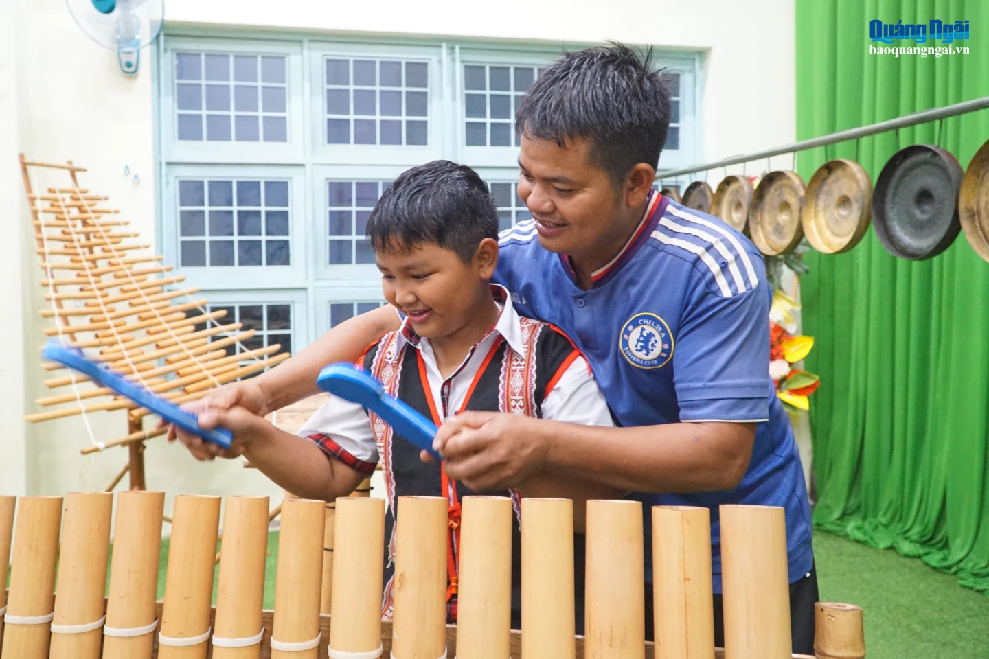 Anh A Áo cầm tay, hướng dẫn em A Hậu Ka từng nhịp gõ.