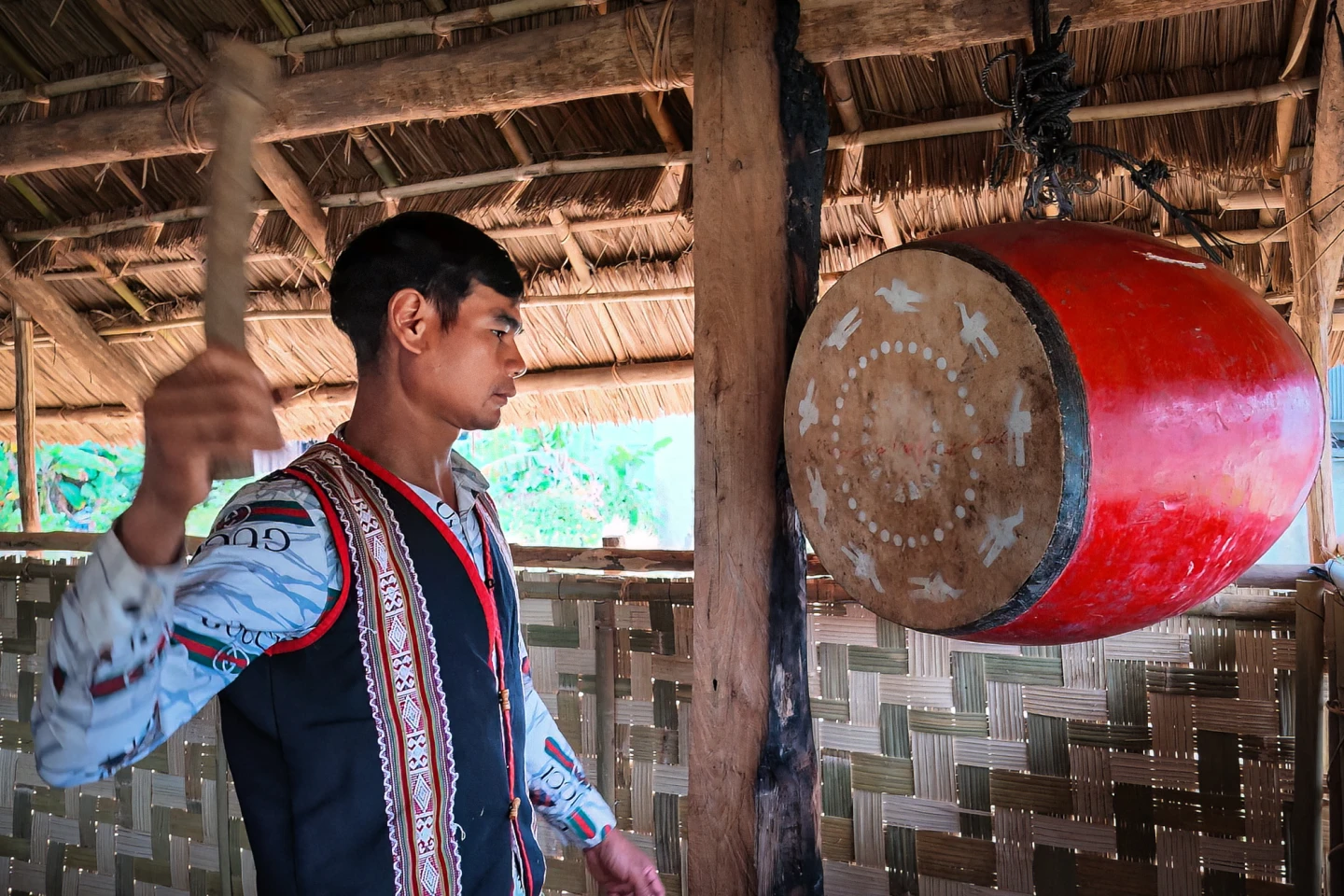 Già làng A Lát đánh trống hiệu thông báo dân làng đến nhà rông làm lễ.